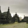 Guimiliau, l'enclos paroissial vu de la rue du Calvaire. L'ensemble comprend une sobre porte triomphale surmontée de deux cavaliers, l'église Saint Miliau, un ossuaire (adossé au flanc gauche du porche de l'église), un calvaire, une chapelle funéraire. 