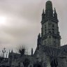 Enclos paroissial de Lampaul-Guimiliau - le porche de style gothique (1533) de l'église Notre-Dame est orné en partie haute d'une statue de saint Michel et d'un ensemble sommital : saint Pol surmonté  de la Vierge et de saint Jean.  