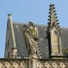 Au-dessus du porche en ogive du mur de clôture qui relie le beffroi à l'église, la statue de l'Ange de Jules Cavelier (1814-1894).